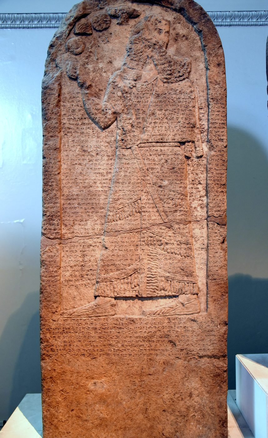 The Kurkh Monolith of Shalmaneser III - a tall basalt stele showing the king carved in relief at the top above columns of dense cuneiform inscription
