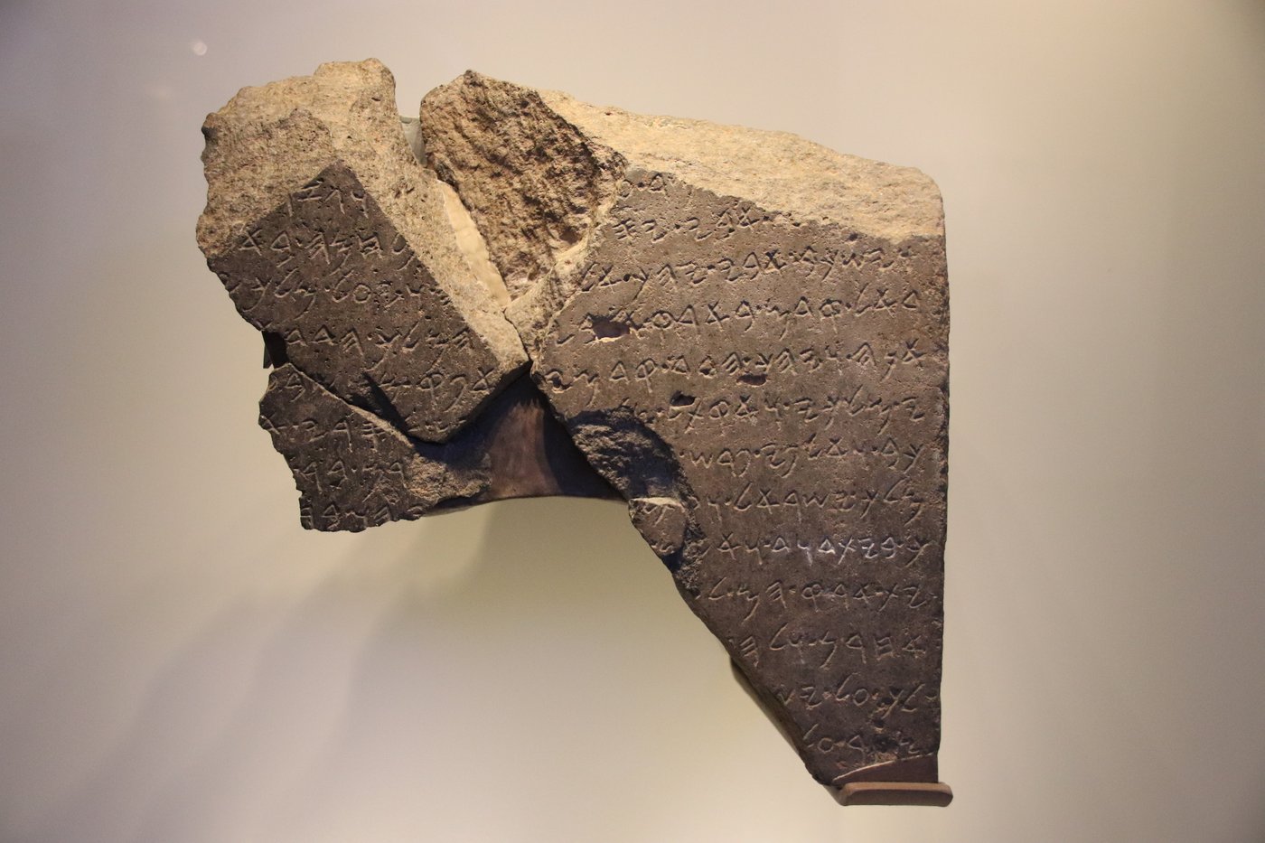 Fragment of an inscribed black basalt stele on museum display.