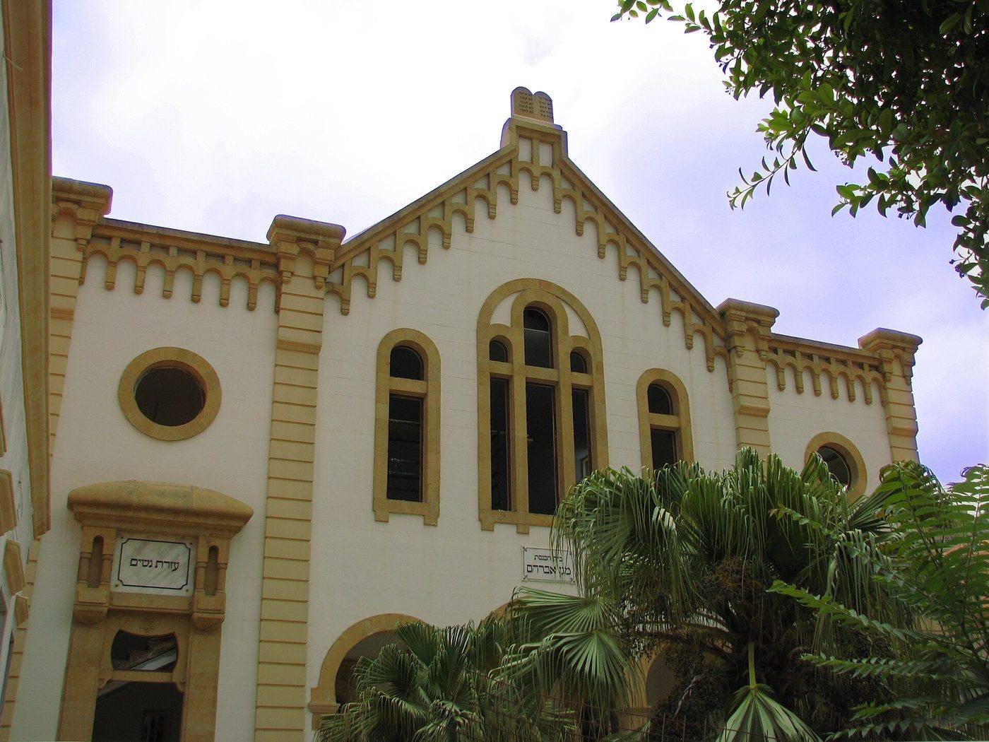 Facade of Maghen Abraham Synagogue in Beirut, with arched windows and trees in front of the restored building.