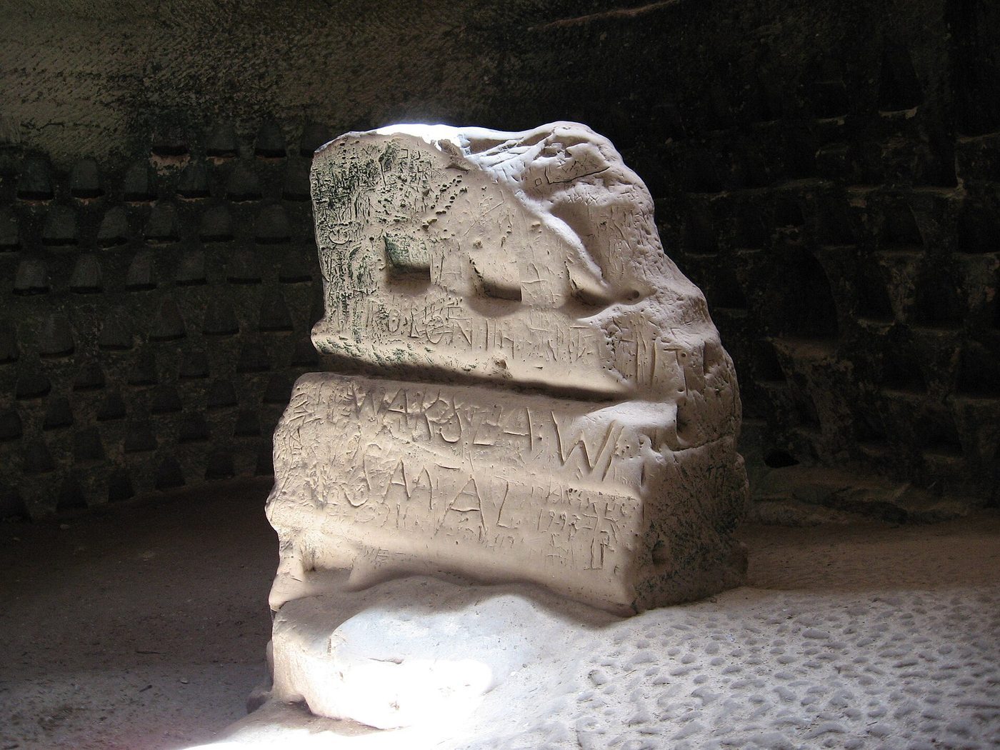 Carved stone feature in a dim chamber at Bet Guvrin, set on a mosaic floor inside the cave landscape.