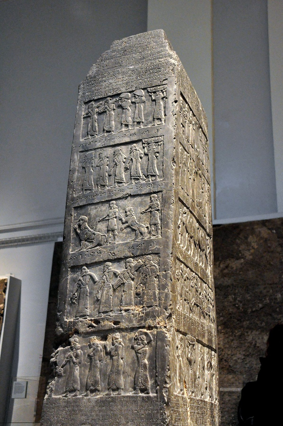 The Black Obelisk of Shalmaneser III displaying five registers of carved relief showing tribute scenes and Assyrian cuneiform inscription