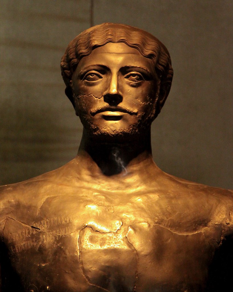 Ancient bronze bust of a bearded crowned man.