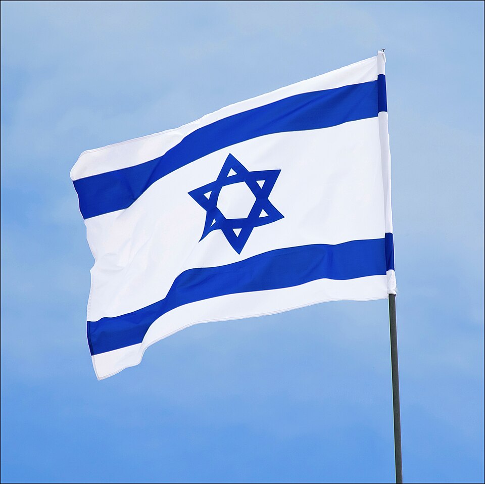 The blue-and-white flag of Israel, two blue stripes and a Star of David on a white field, flying in the wind at Yad LaShiryon, Latrun.