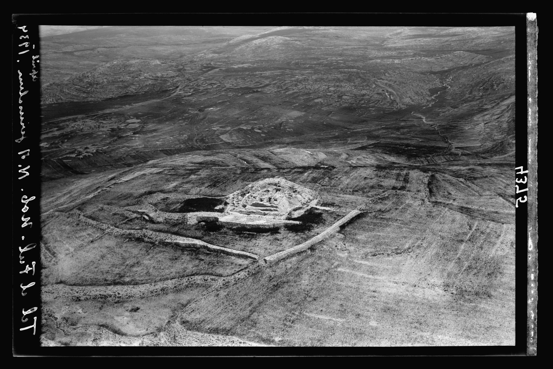 Aerial view of excavated stone fortress corner on a hilltop, showing foundation walls cut into bedrock.