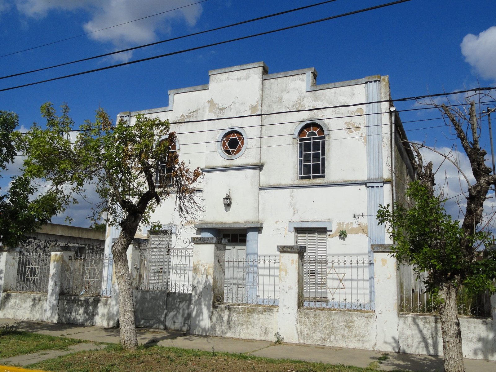 The Workers' Synagogue in Moisés Ville, a white synagogue building with a Star-of-David rose window on a quiet street under a blue sky