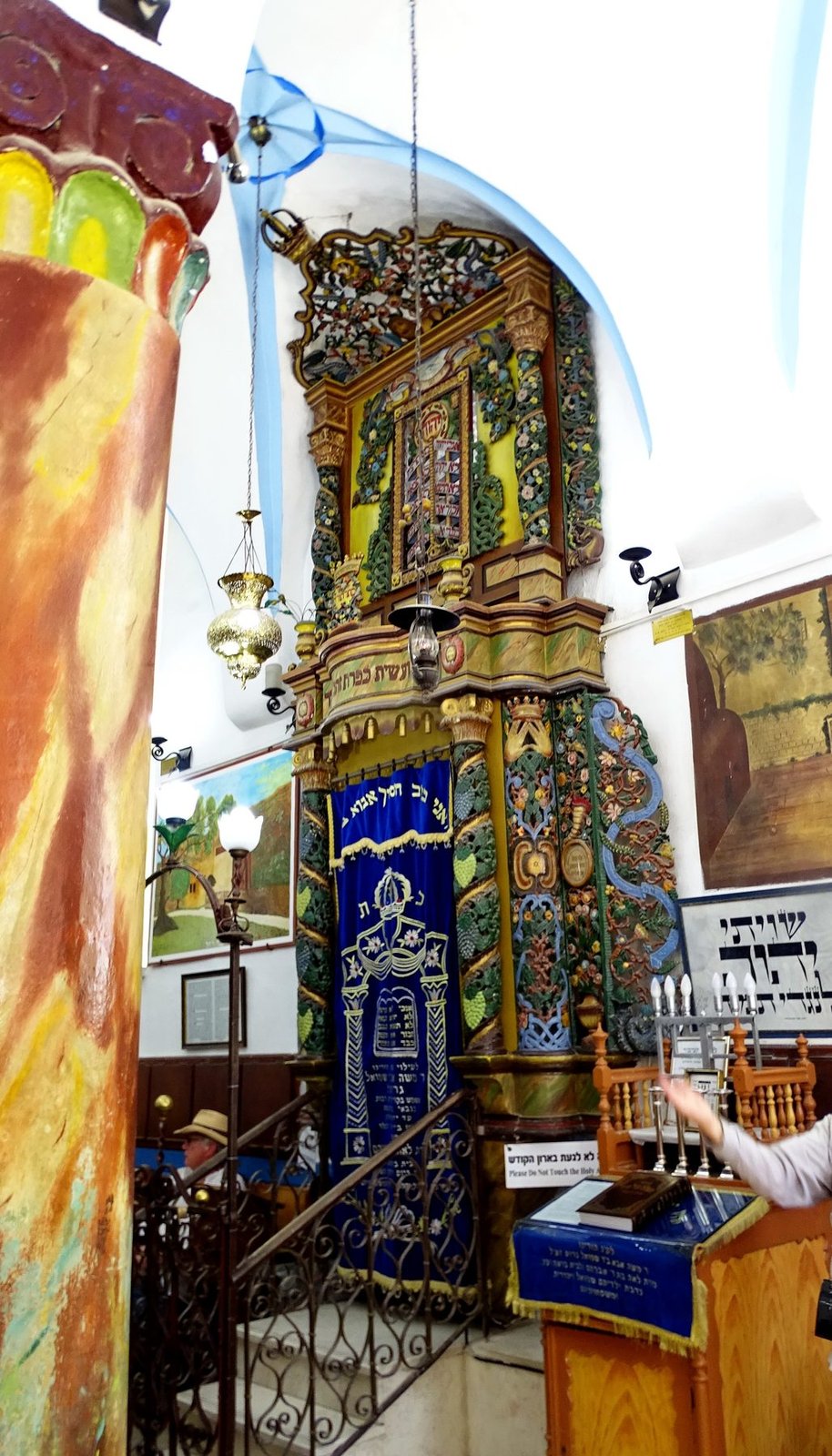 The elaborately carved and brightly painted Torah ark of an old Safed synagogue, hung with lamps