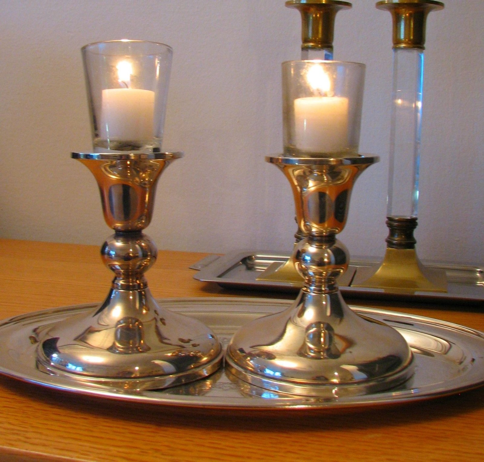 A woman in traditional dress sits at a table set for Shabbat, candles lit, in a painting by Isidor Kaufmann