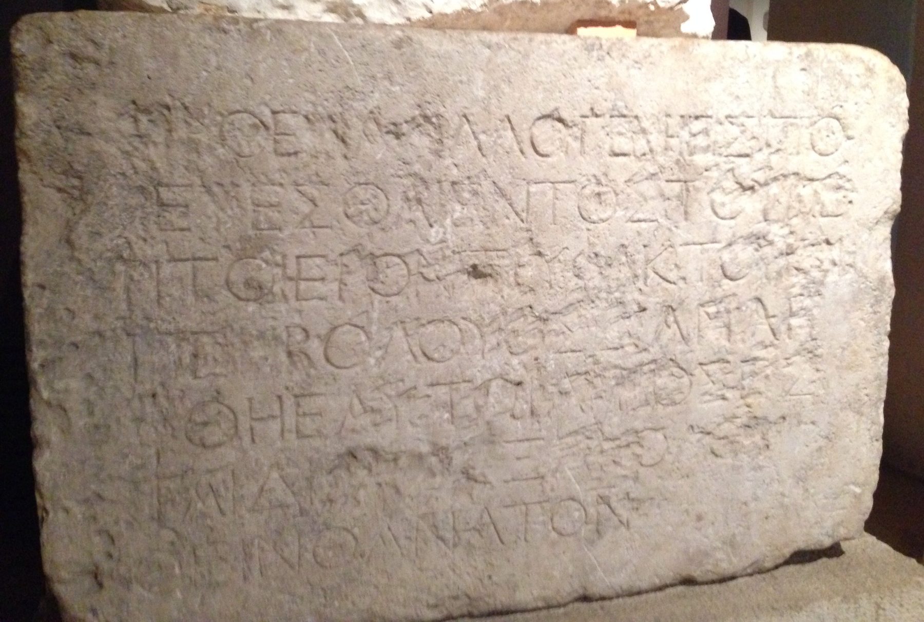 Ancient limestone slab with Greek text carved into its surface, preserved as a museum artefact.