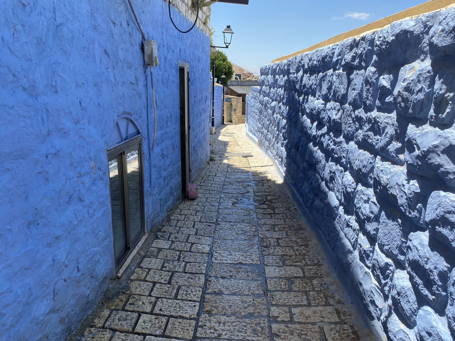 Narrow alley lined with blue-painted walls in the old city of Safed