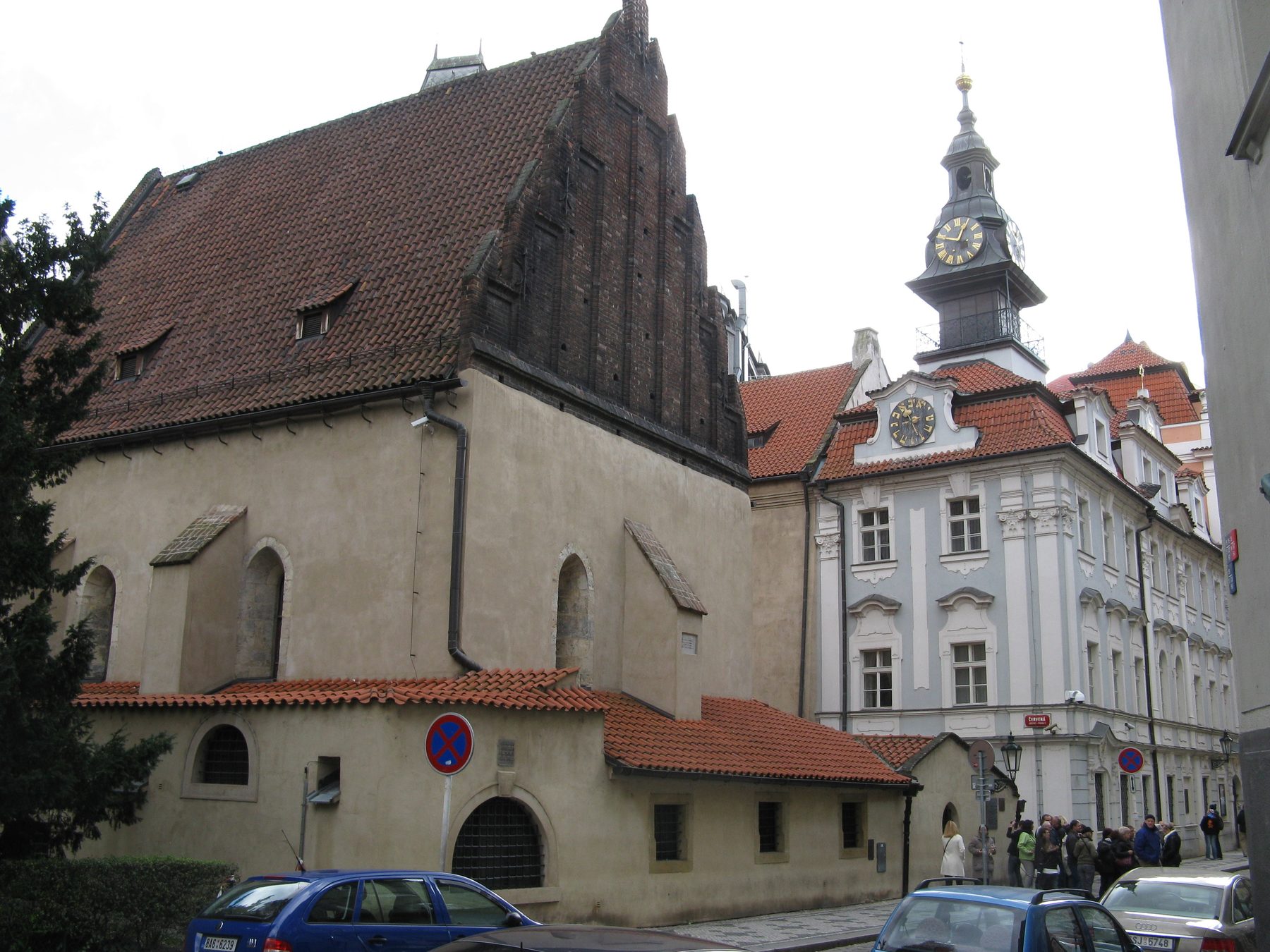 The exterior of the Altneuschul synagogue in Prague showing the low brick building with dark roof, arched windows, and stepped gable.
