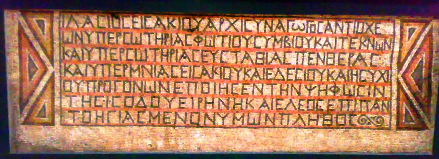A mosaic floor panel inscribed with Greek donor dedications in stone tesserae, framed by geometric borders.