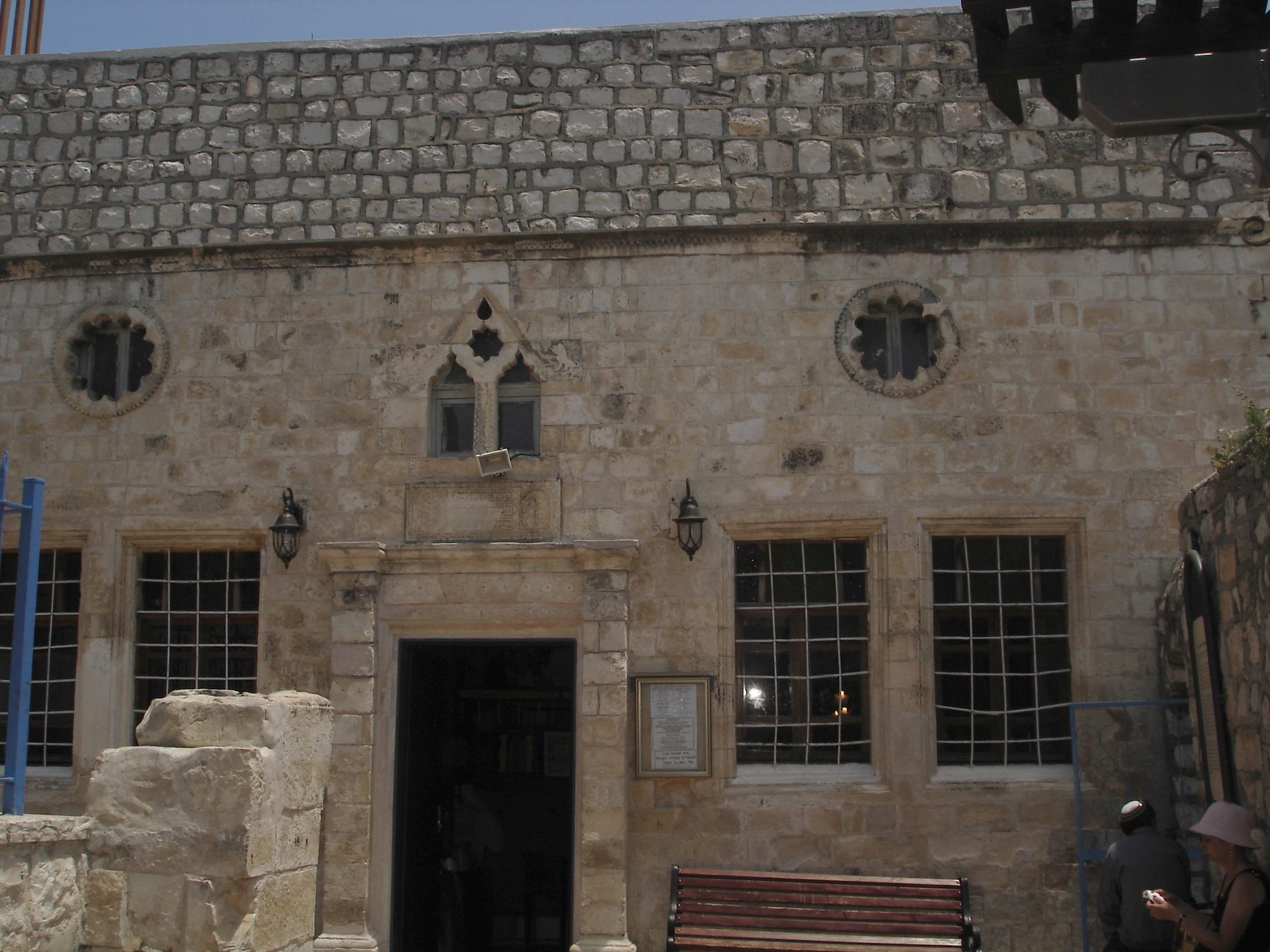 Exterior of the Ari Ashkenazi Synagogue in Safed, showing weathered stone facade with multiple windows and carved stone details.