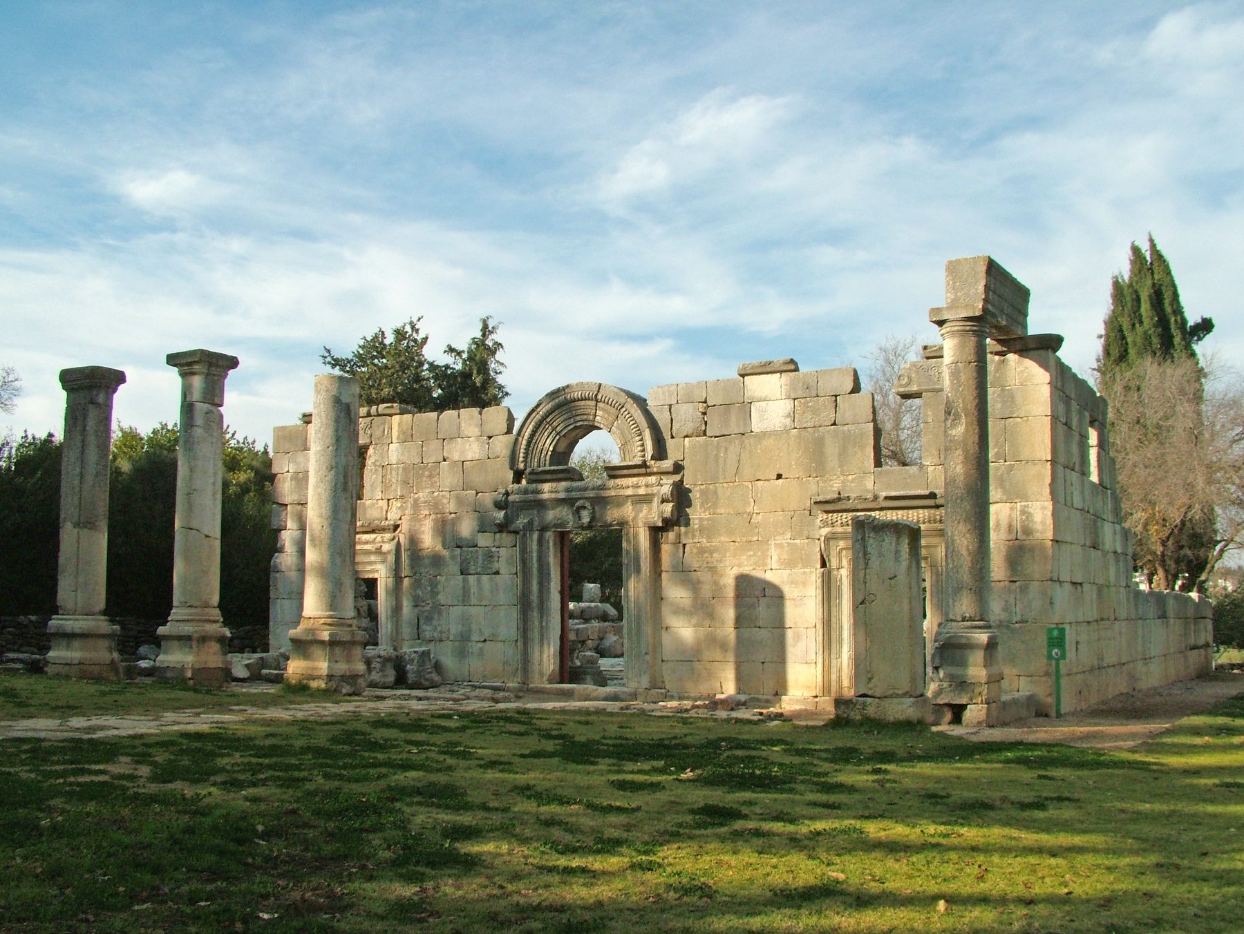 Stone facade of the Baram synagogue with three doorways flanked by columns, a central arched gateway with carved decoration, in the Upper Galilee.