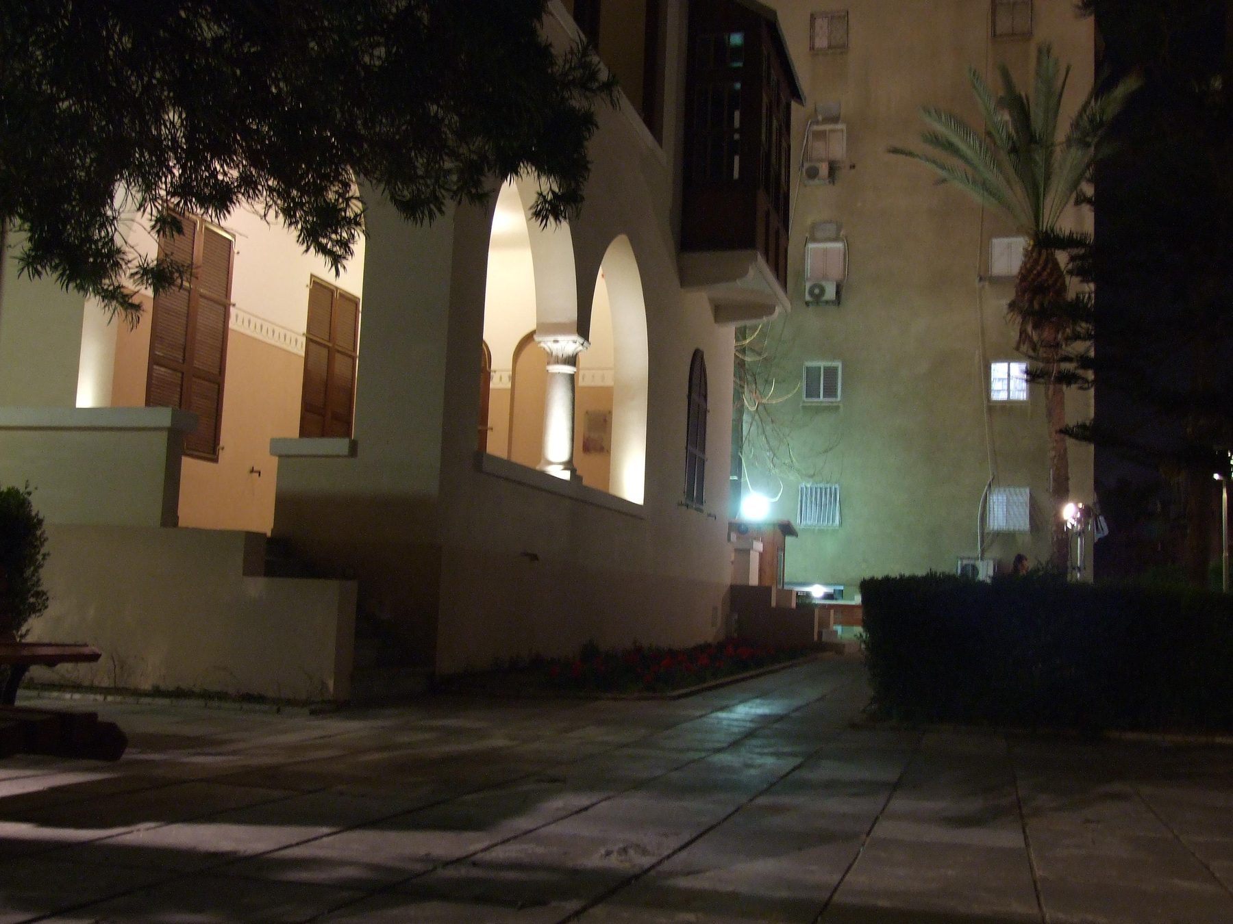 Night-time view of the Bialik House exterior showing whitewashed walls, arched windows and dark wooden shutters