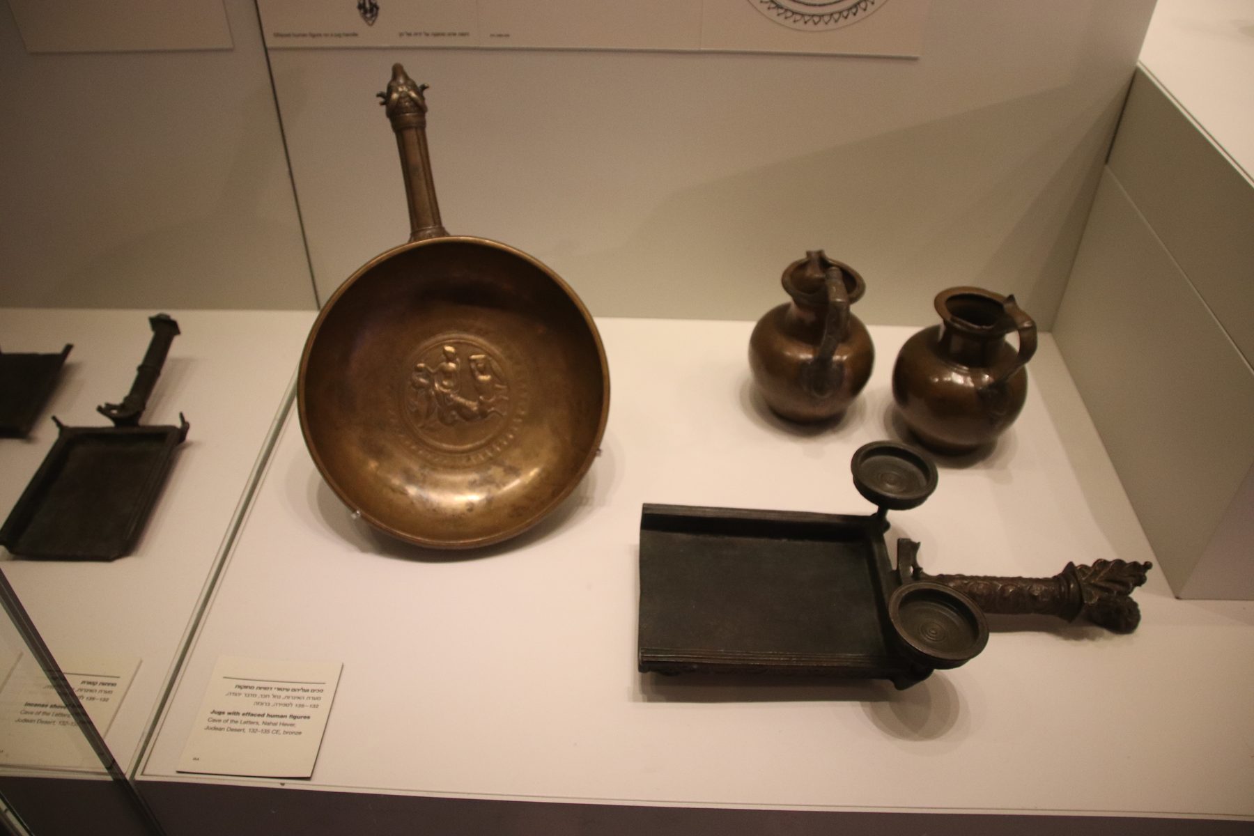 Roman-period bronze vessels, keys, and household objects displayed in a museum case