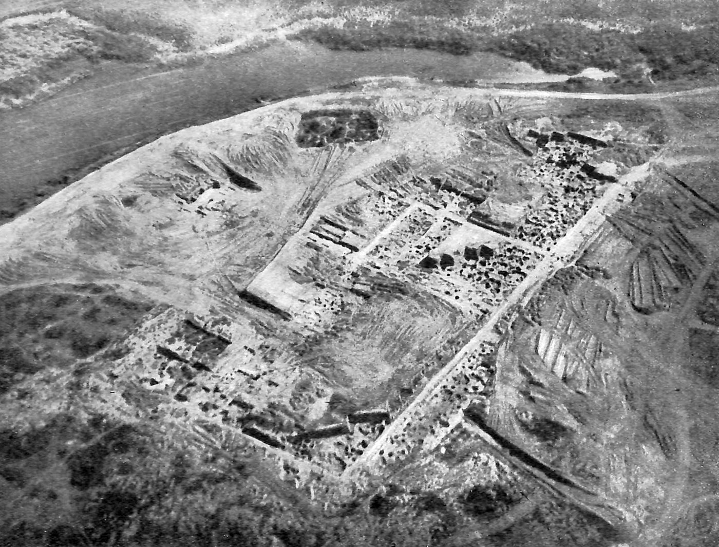 An aerial photograph of a riverside excavation showing the outline of a large rectangular fortress.