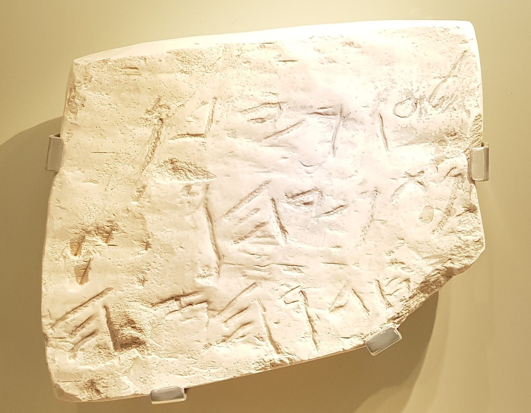 Limestone plaque with carved Hebrew inscriptions in relief, mounted on display brackets