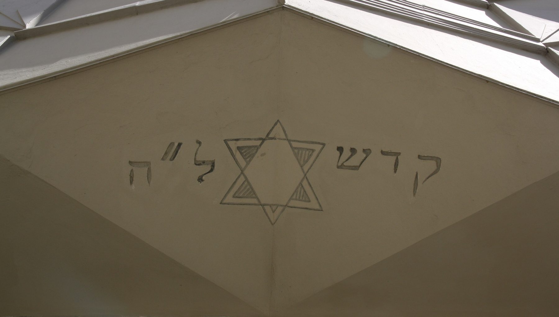 Interior ceiling detail of the Great Synagogue of Livorno showing a Star of David with Hebrew text carved in white stone.