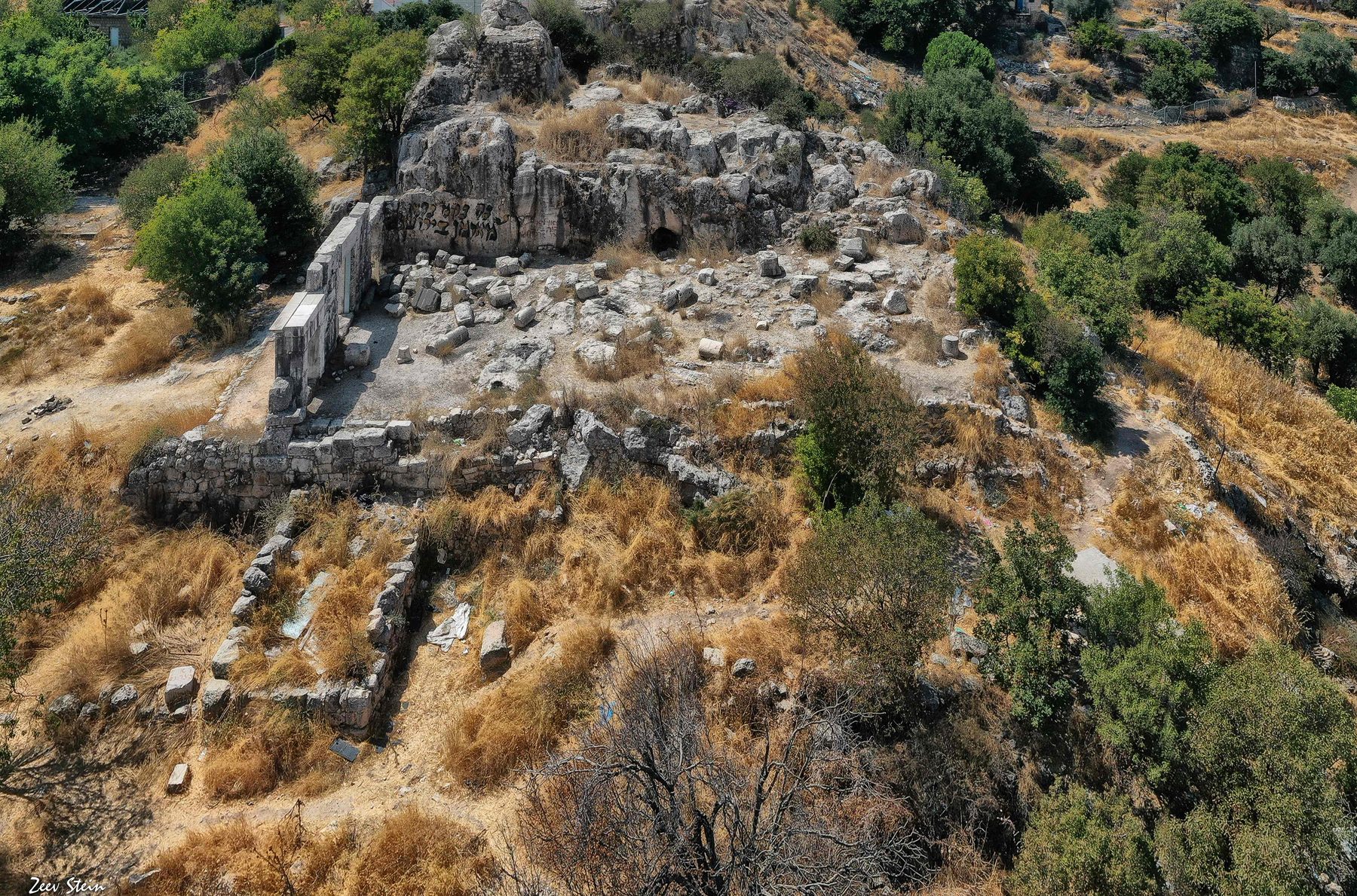 Aerial view of the Meiron Synagogue ruins, showing large rectangular stone blocks and architectural remains set on a Mediterranean hillside above Safed in the Upper Galilee.