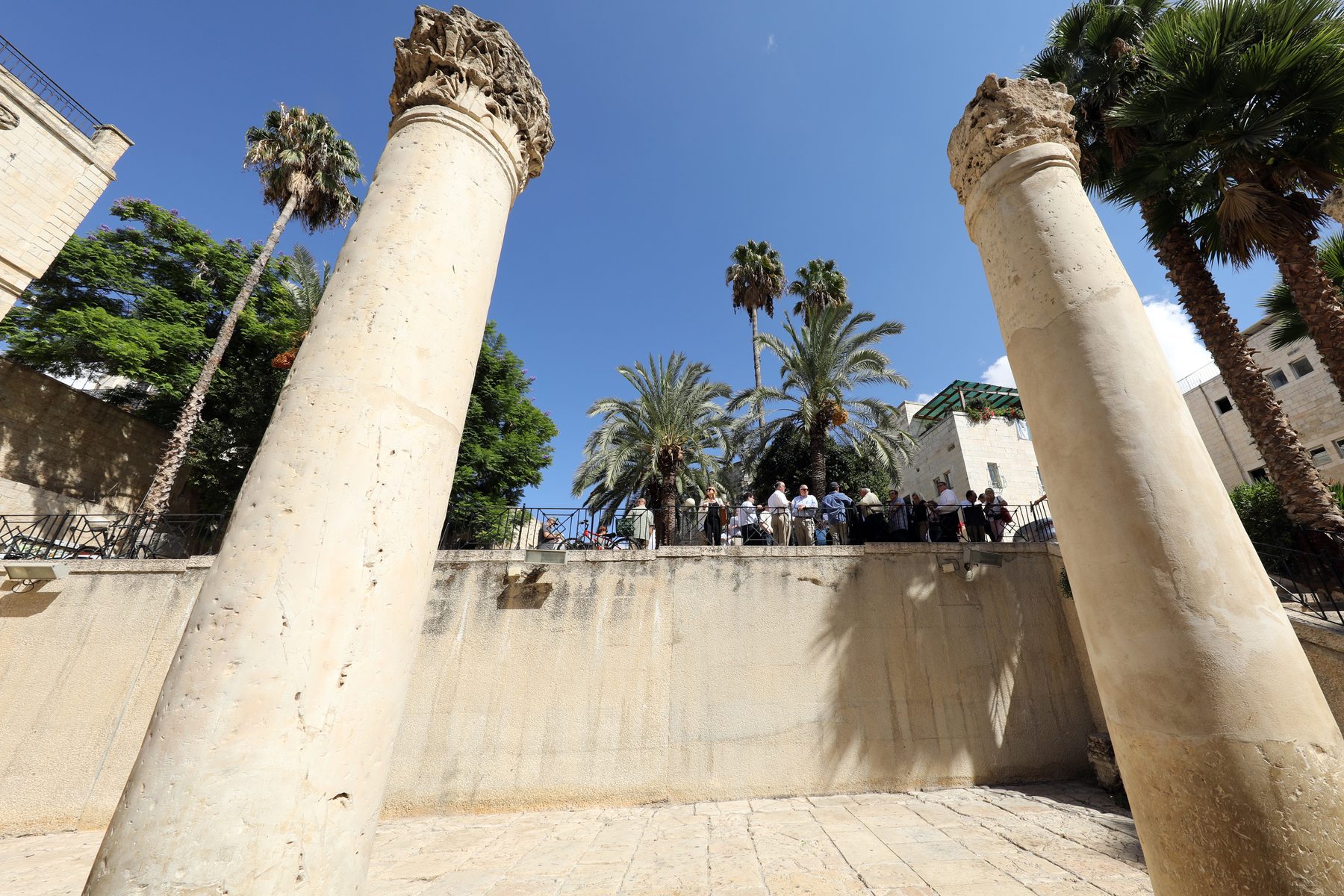 Corinthian columns of the Byzantine Cardo, viewed from below, with palm trees and modern Jerusalem buildings