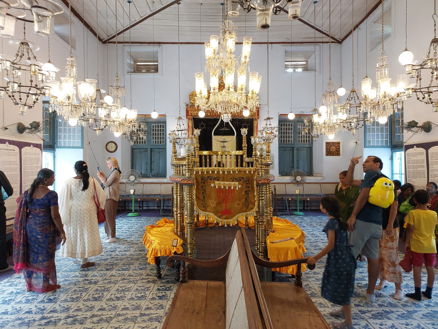 Interior of the Paradesi Synagogue in Mattancherry, Kochi, with brass chandeliers, ornate bimah and blue Chinese ceramic tiles.