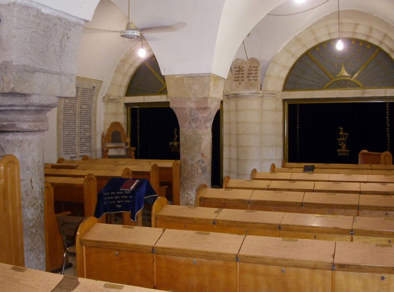 Interior of the low, vaulted stone chamber of the Ramban Synagogue in Jerusalem's Old City, its floor set below the level of the surrounding street.
