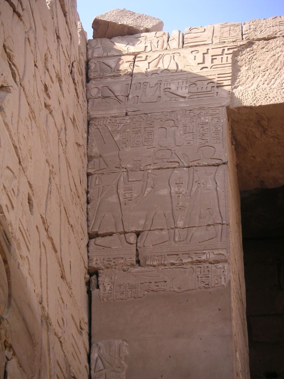 Carved relief on the Bubastite Portal at Karnak temple showing Pharaoh Sheshonq I before rows of bound captive figures, each standing on an oval name-ring of hieroglyphs naming a conquered town.