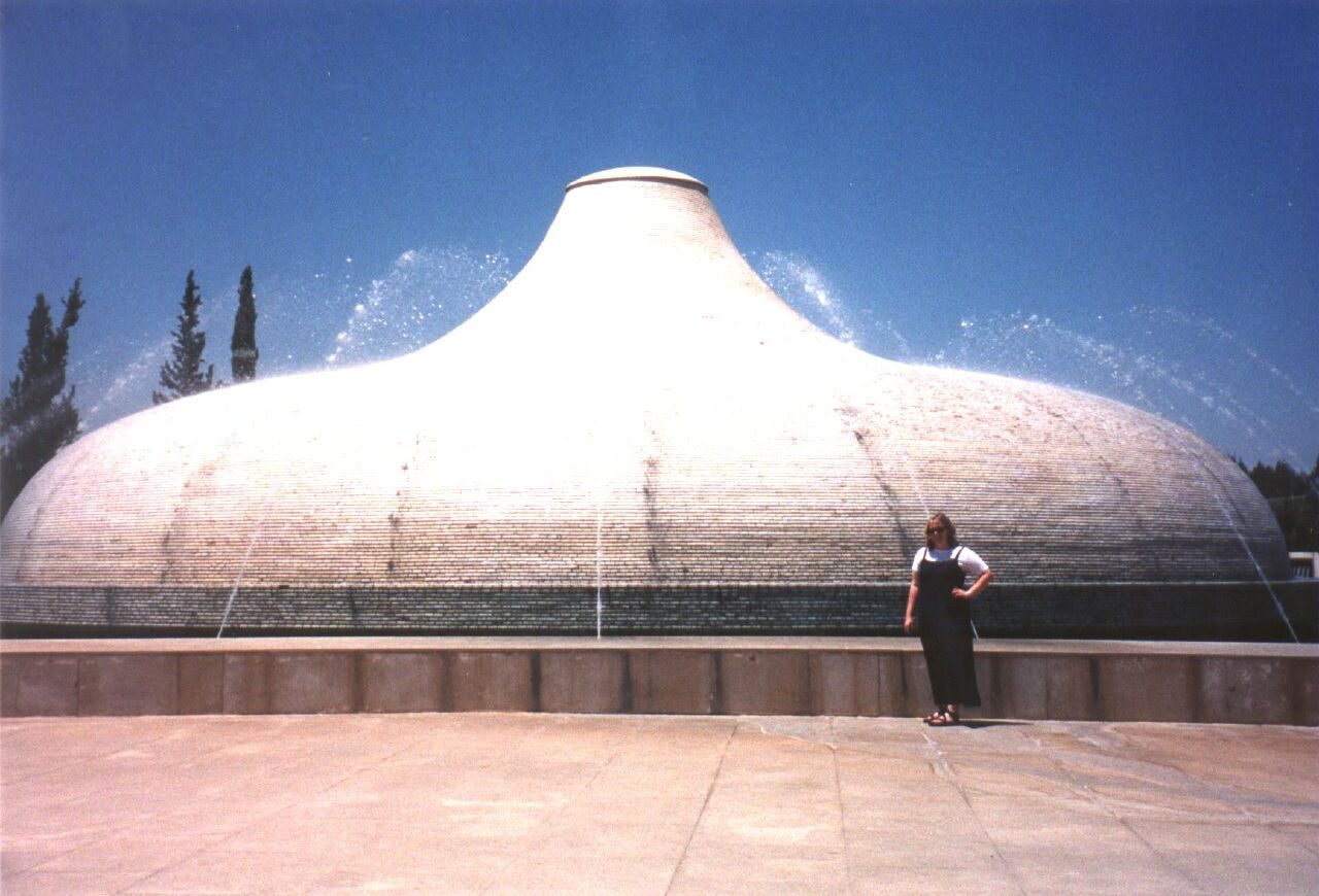 The white ribbed dome of the Shrine of the Book at the Israel Museum, with cypress trees and a reflecting pool in the foreground.
