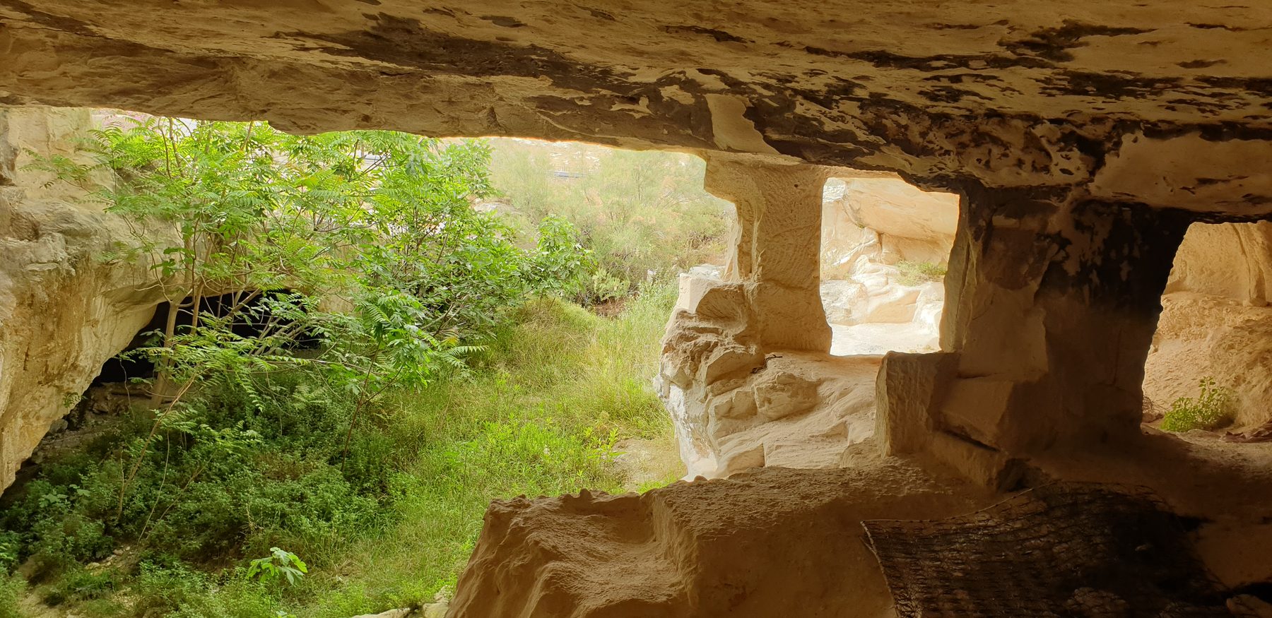Interior of the rock-cut quarry where stone purity vessels were carved, showing limestone walls with rectangular openings