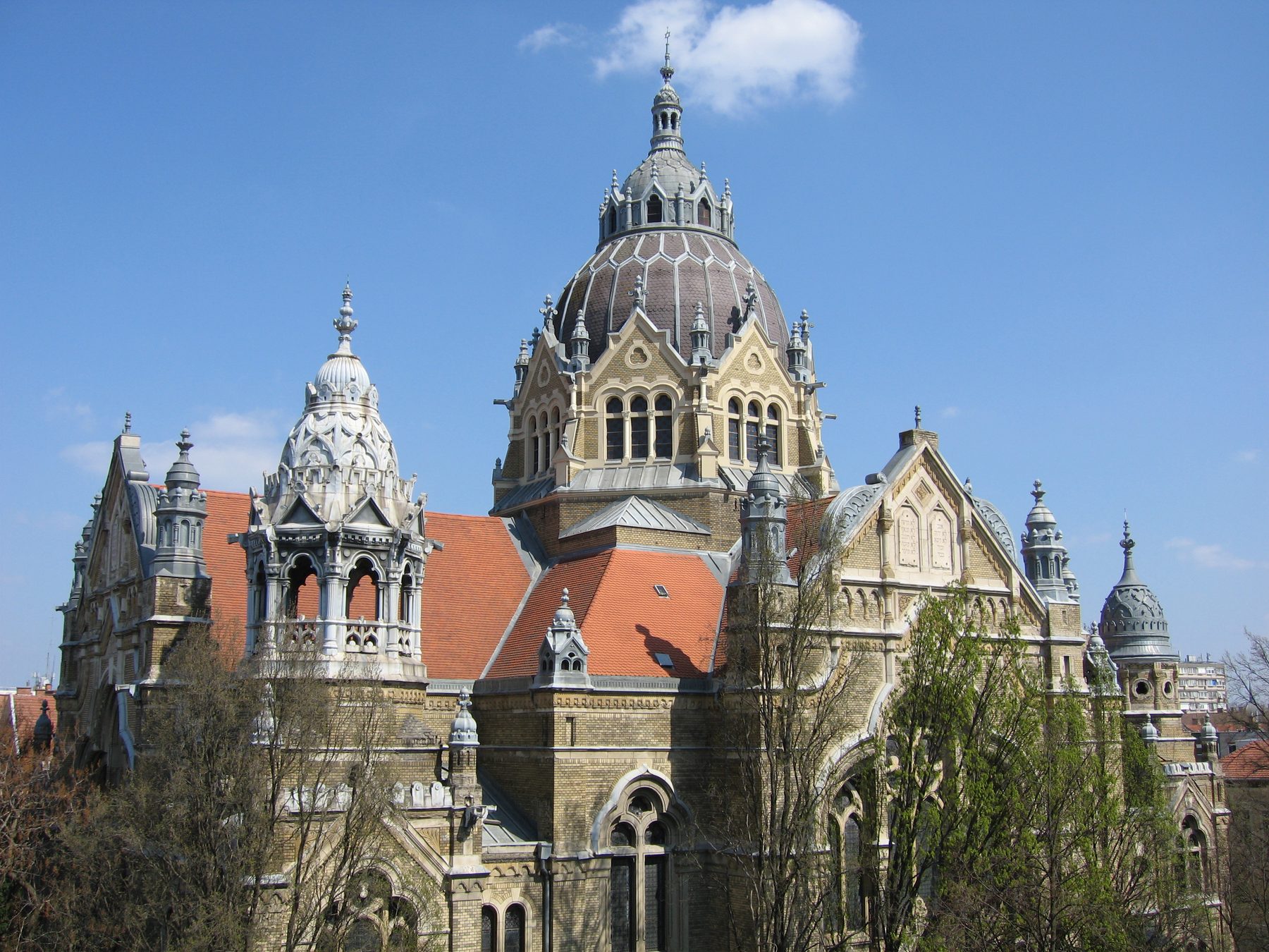 Exterior view of the Szeged New Synagogue showing its large cream-coloured dome, Art Nouveau stone facades, and decorative towers.
