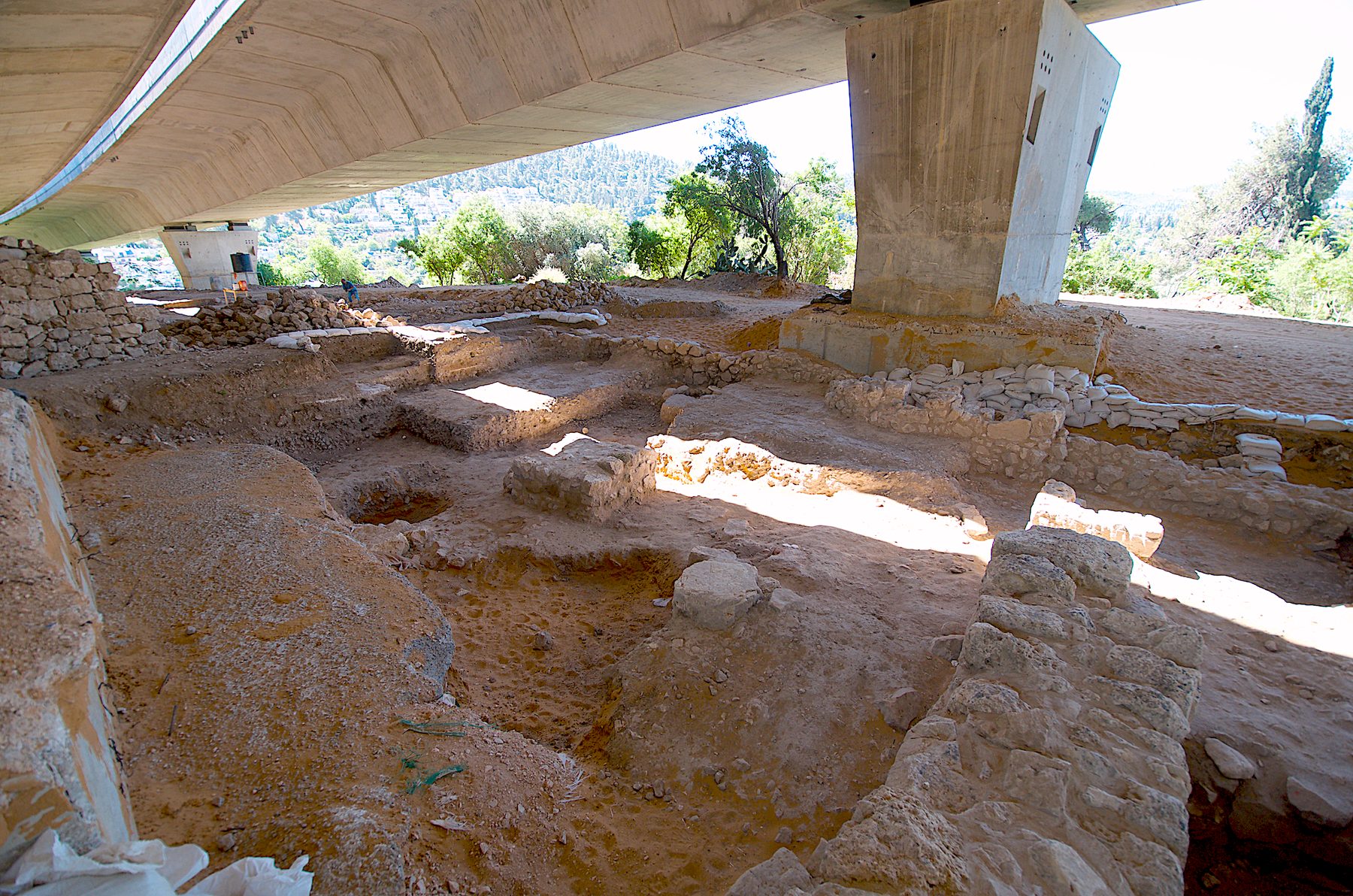 Stone foundations and remains of the Tel Moza temple excavation under a protective shelter, showing courtyard and altar platform.