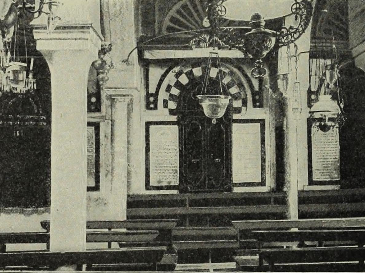 Interior of the Great Synagogue of Tunis with benches and wall plaques.