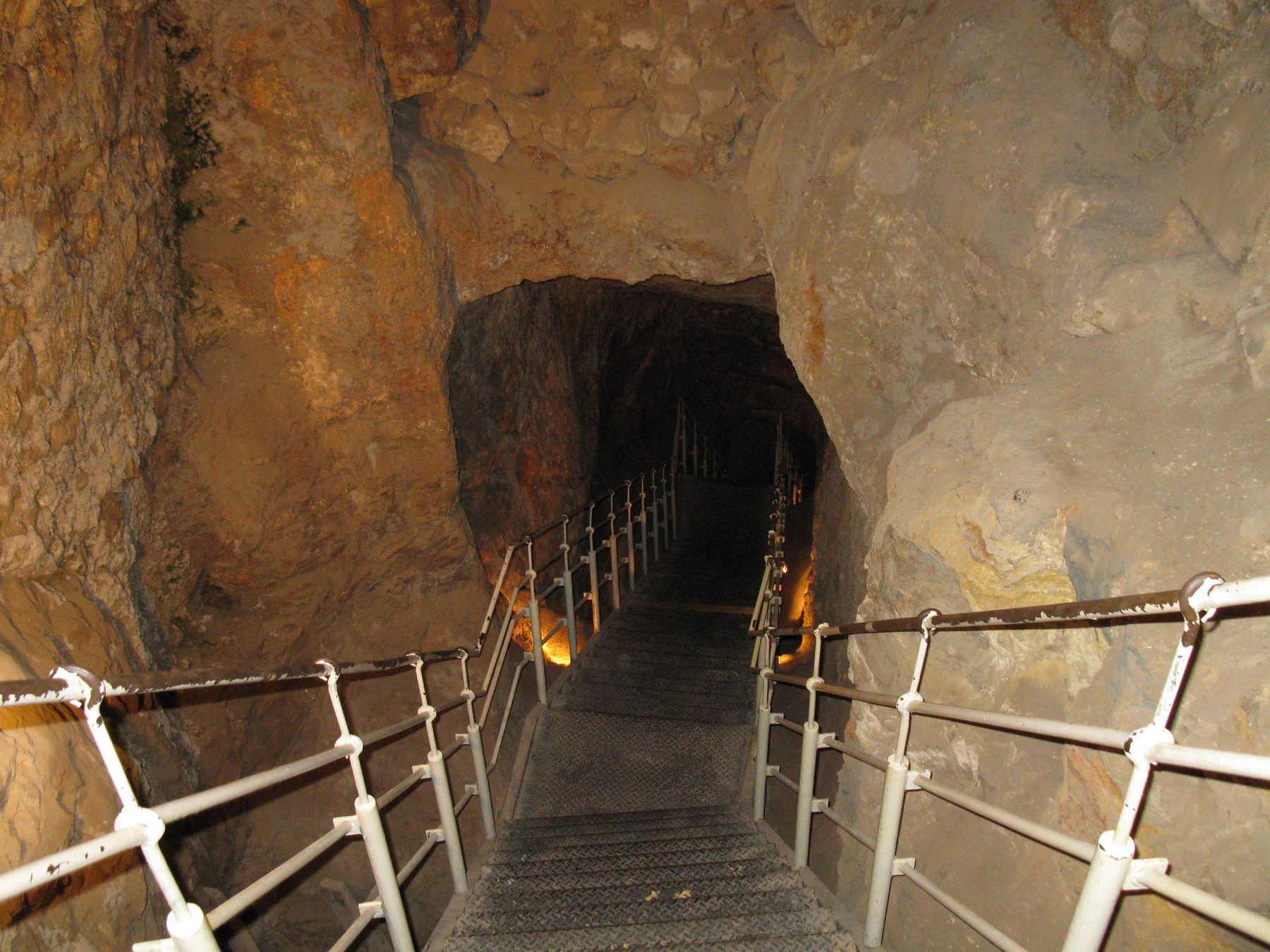 Underground passage of Warren's Shaft with modern metal safety railings descending into ancient rock-cut tunnel
