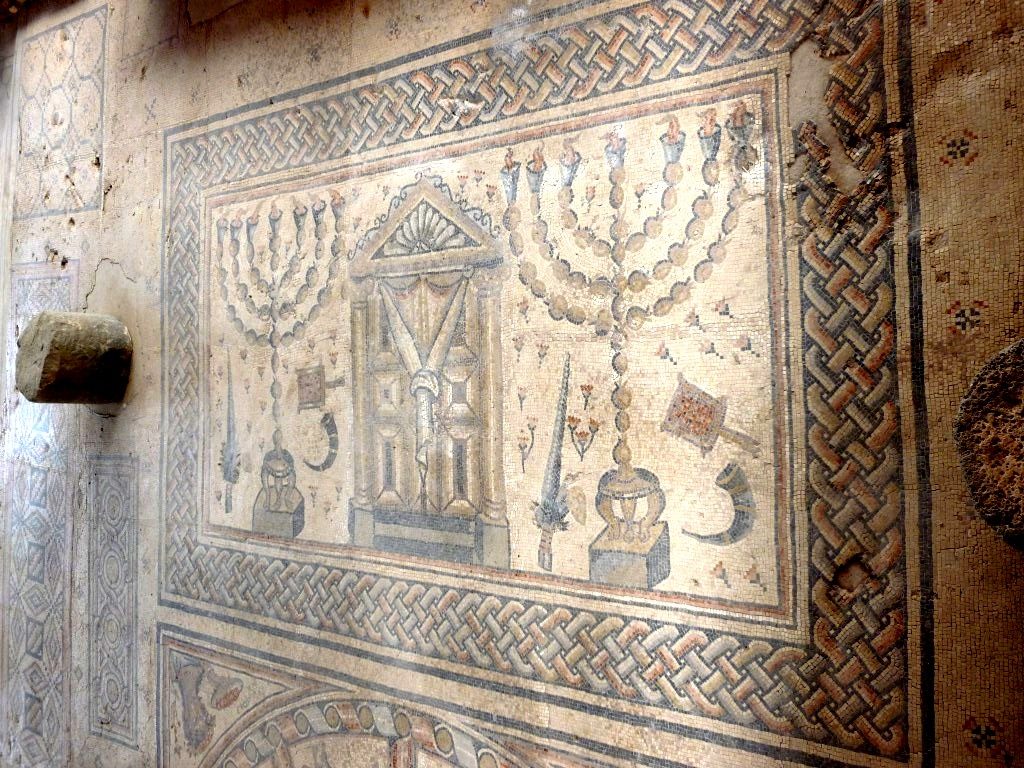 Mosaic floor panel in the Hammat Tiberias synagogue showing the Torah ark flanked by two seven-branched menorot and ritual objects including a shofar and incense shovel